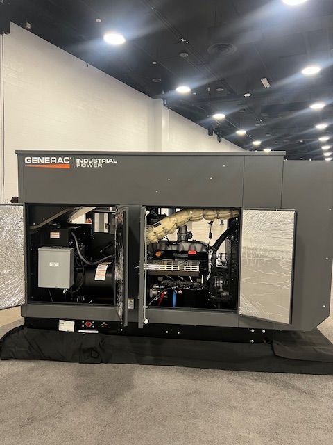 Large gray industrial generator unit with open access panels on display indoors.