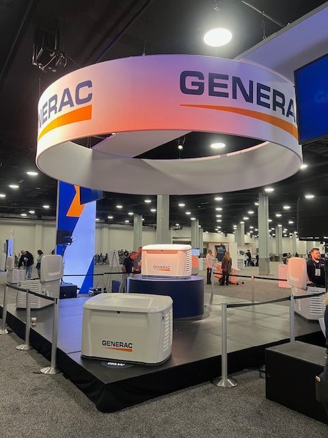 Trade show booth with a circular GEAC GENERAL sign and white display equipment on a raised platform