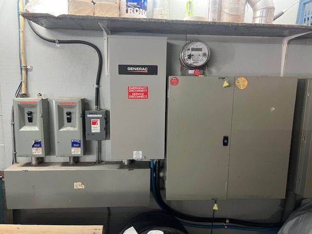 Utility room with electrical panels, gauges, and conduit mounted on a wall.