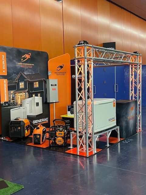 Black-and-orange portable generator display booth with truss frame and equipment at an indoor trade show