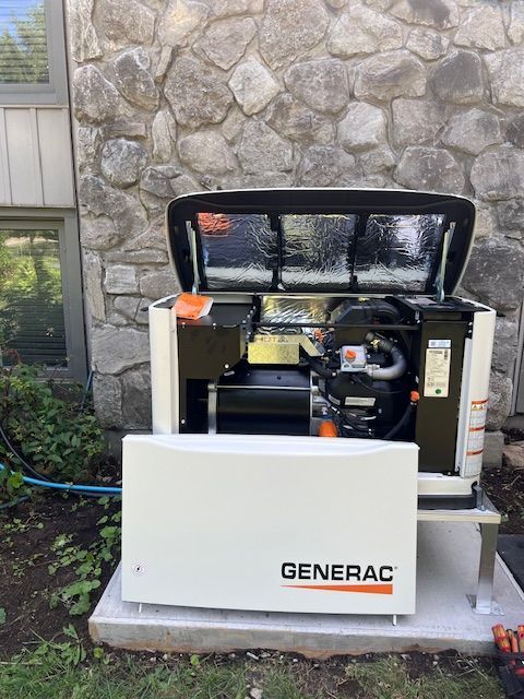 Open Generac backup generator with white cover in front of a stone building