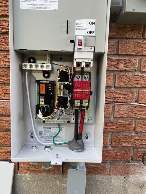 Open electrical service panel with exposed wiring mounted on a brick wall
