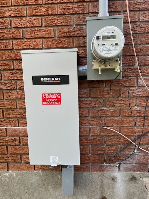 Generac backup generator beside a utility meter on a brick exterior wall