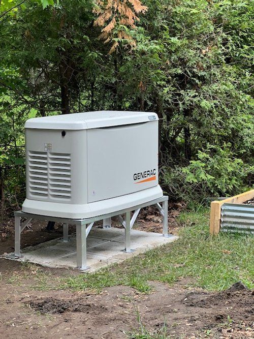 A generator is sitting on top of a concrete platform in the middle of a field.