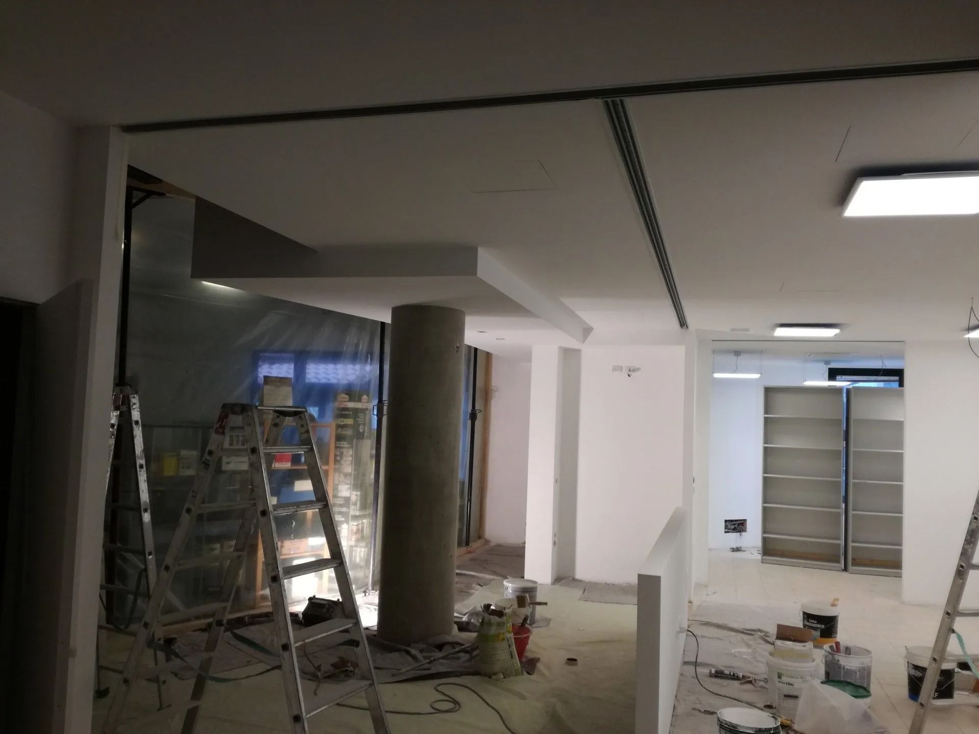 Locale parzialmente ristrutturato con scale, attrezzi e materiali edili sotto un soffitto basso.