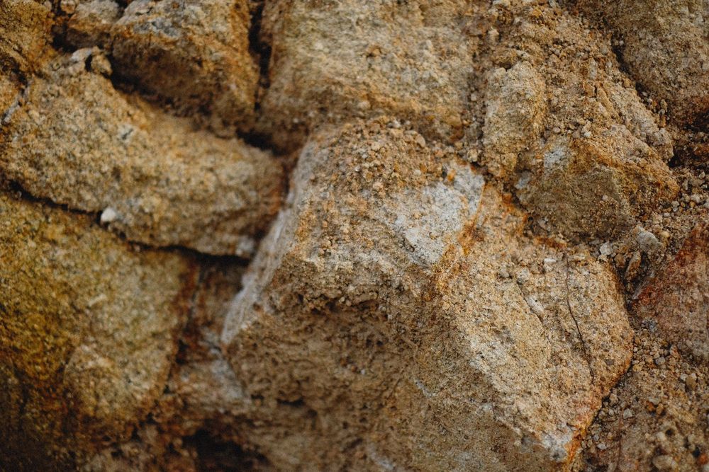 Primo piano di rocce ruvide color beige e marrone con una superficie granulosa e irregolare.