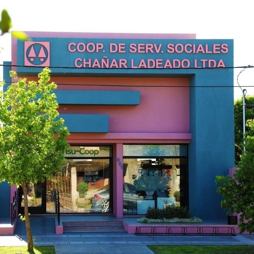 Fachada de Coop. de Serv. Sociales Chañar Ladeado Ltda., un local comercial azul y rosa con puertas de cristal.