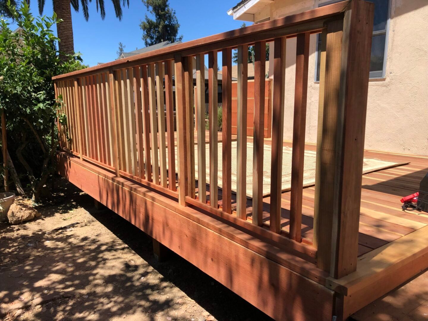 A wooden deck with a railing is sitting in front of a house.