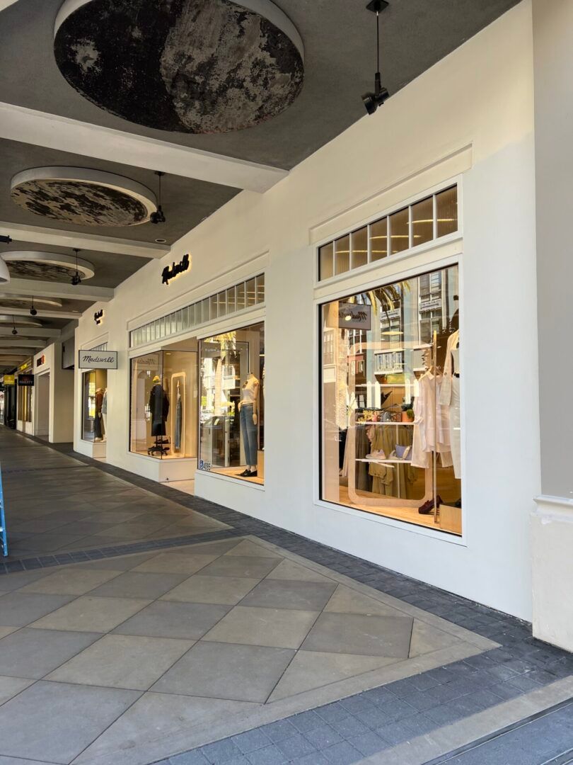 A white building with a lot of windows and mannequins in the windows.