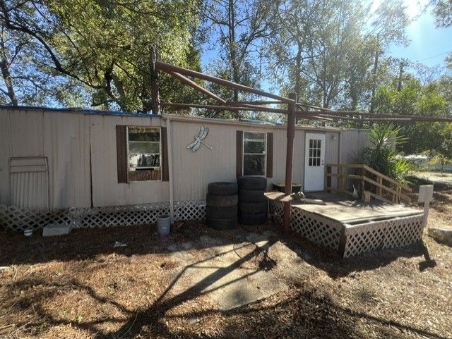 Small weathered shed with a porch, tires stacked by the door, and a raised platform in a wooded yard.