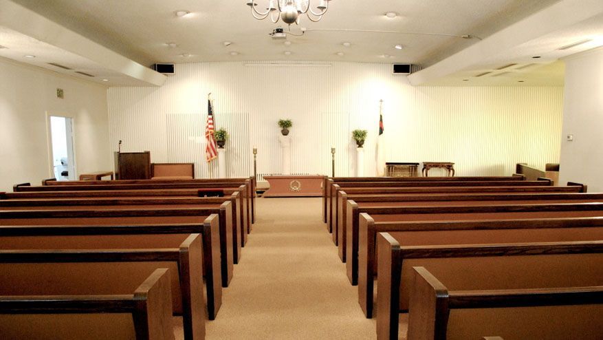 an empty church with rows of wooden benches and a chandelier .