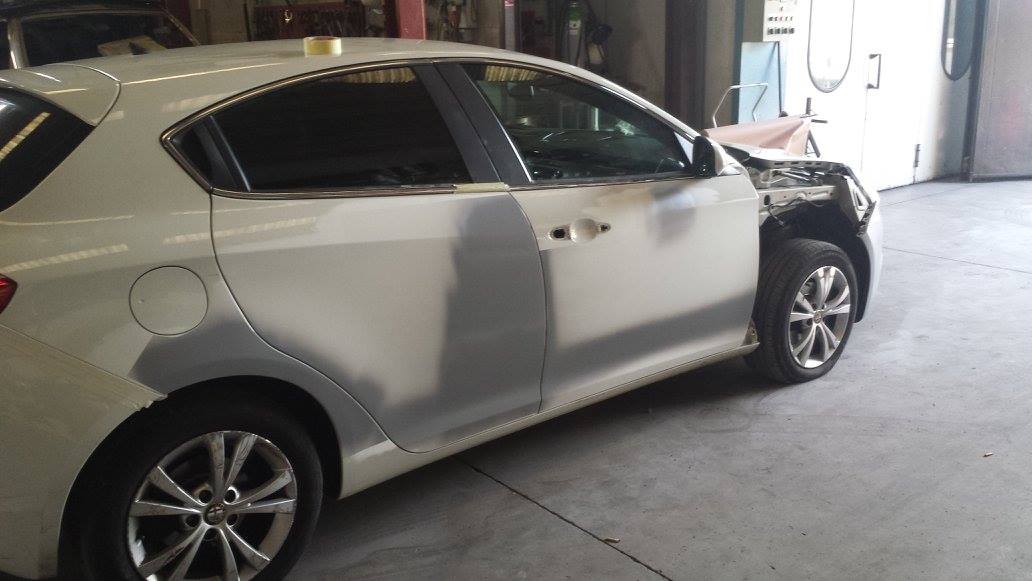 Auto bianca con carrozzeria riparata in officina. Parafango anteriore e pannelli delle portiere sono stati trattati con primer.