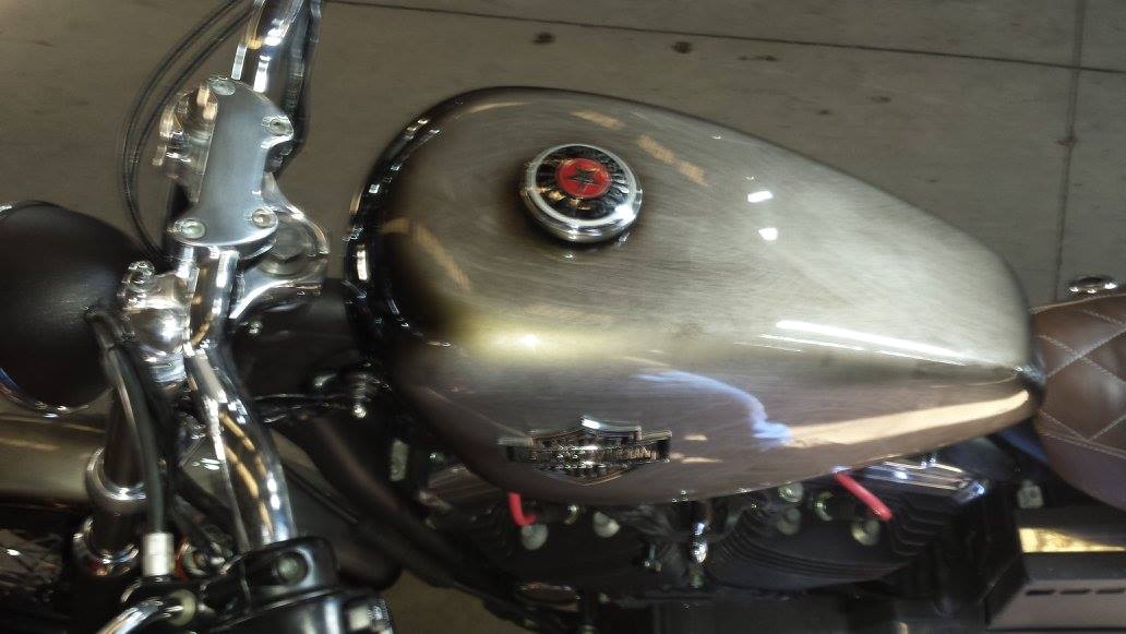 Serbatoio per motocicletta, argento con tappo rosso, manubrio cromato e dettagli in pelle.