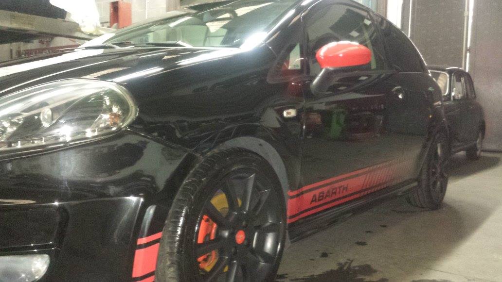 Auto Abarth nera con dettagli rossi e gialli; parcheggiata al chiuso.