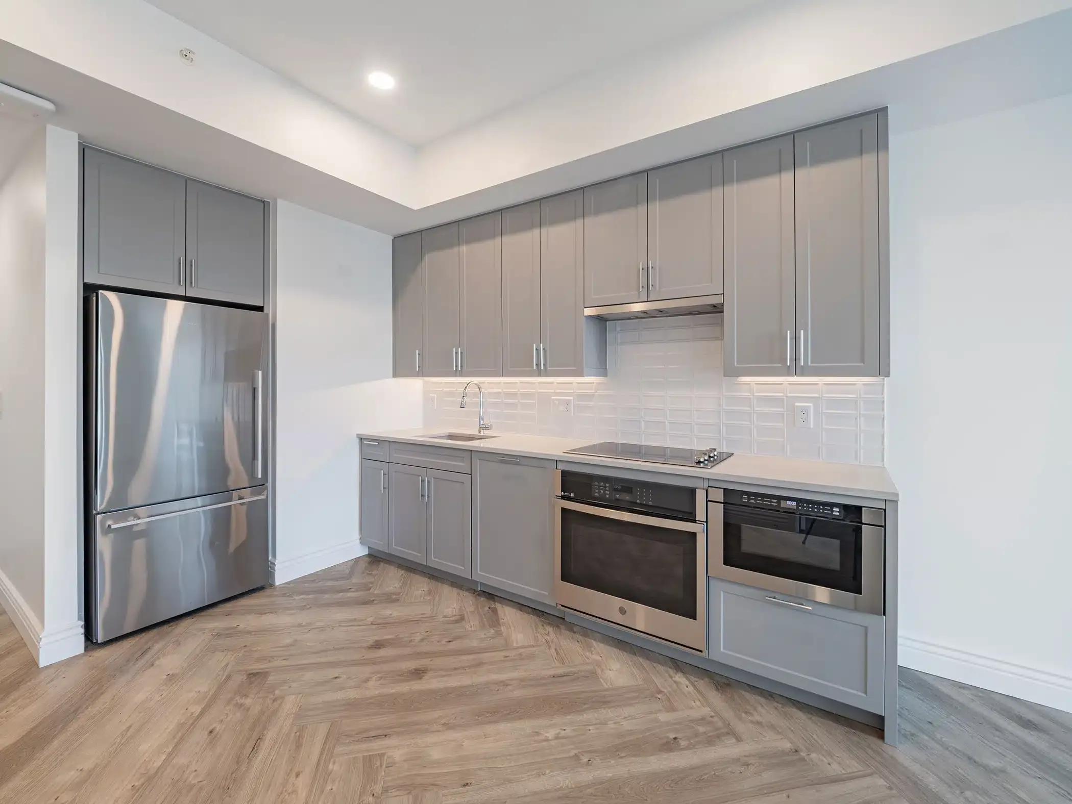 A kitchen with stainless steel appliances and gray cabinets