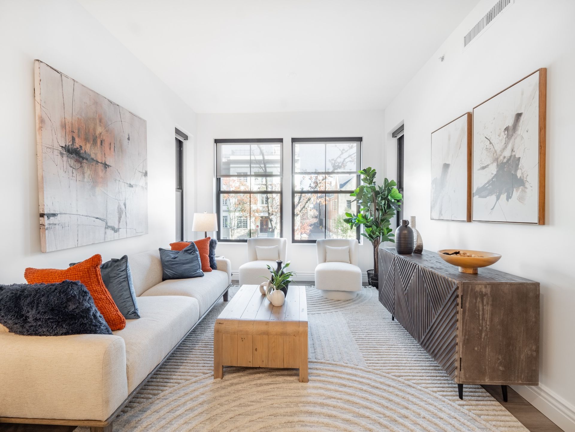 A living room with a white couch , two chairs , a coffee table and a rug.
