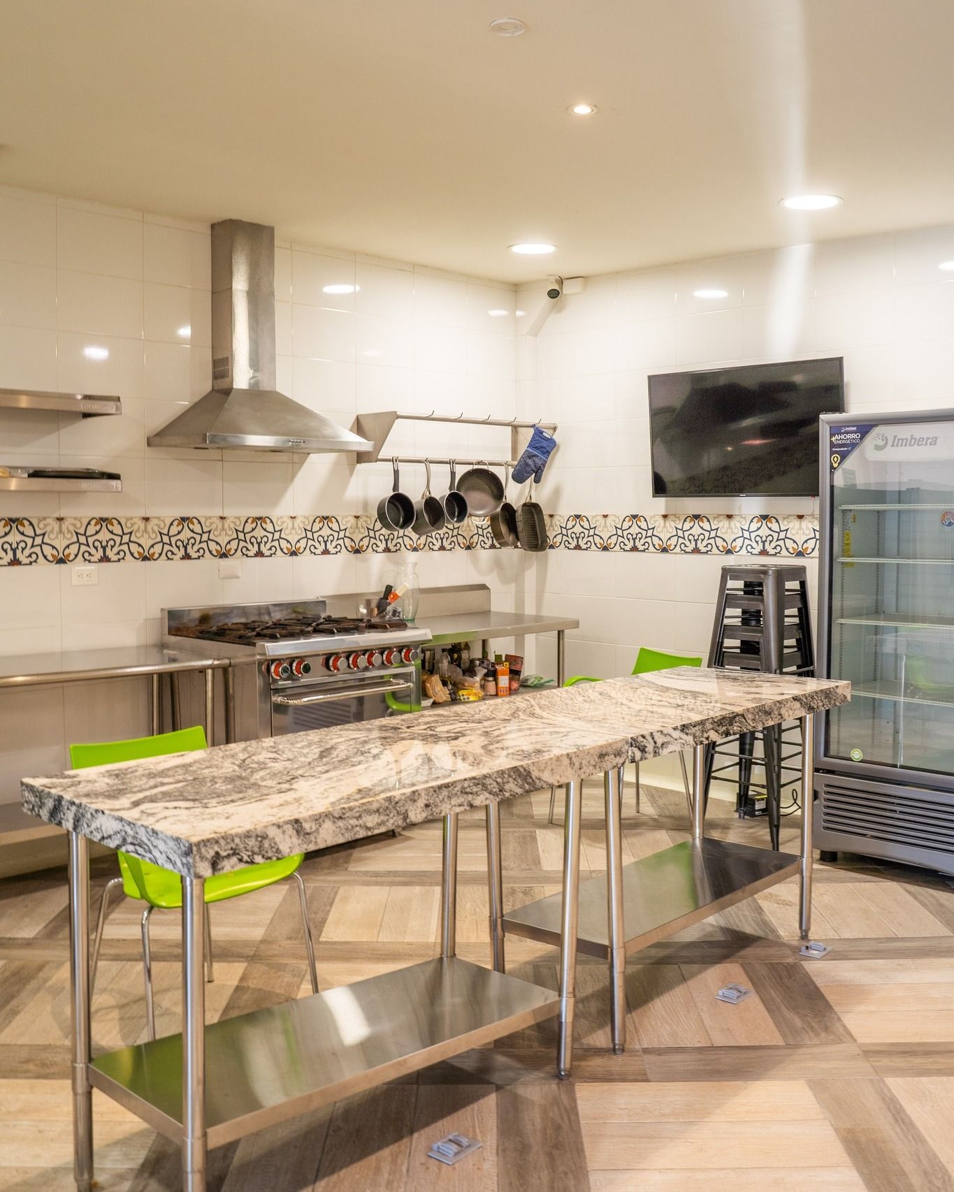 Cocina moderna con isla de granito, estufa de acero inoxidable, utensilios colgantes y enfriador de bebidas de vidrio.