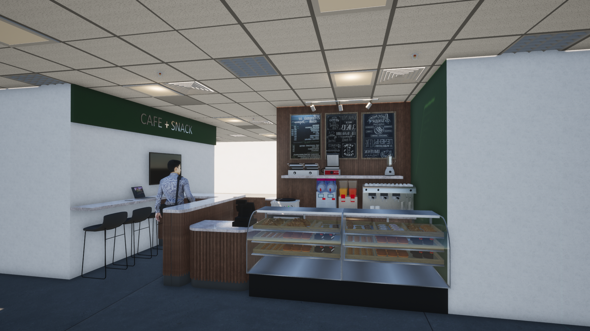 Pequeña cafetería con vitrina, mostrador y una persona de pie junto a la pared en una habitación luminosa.