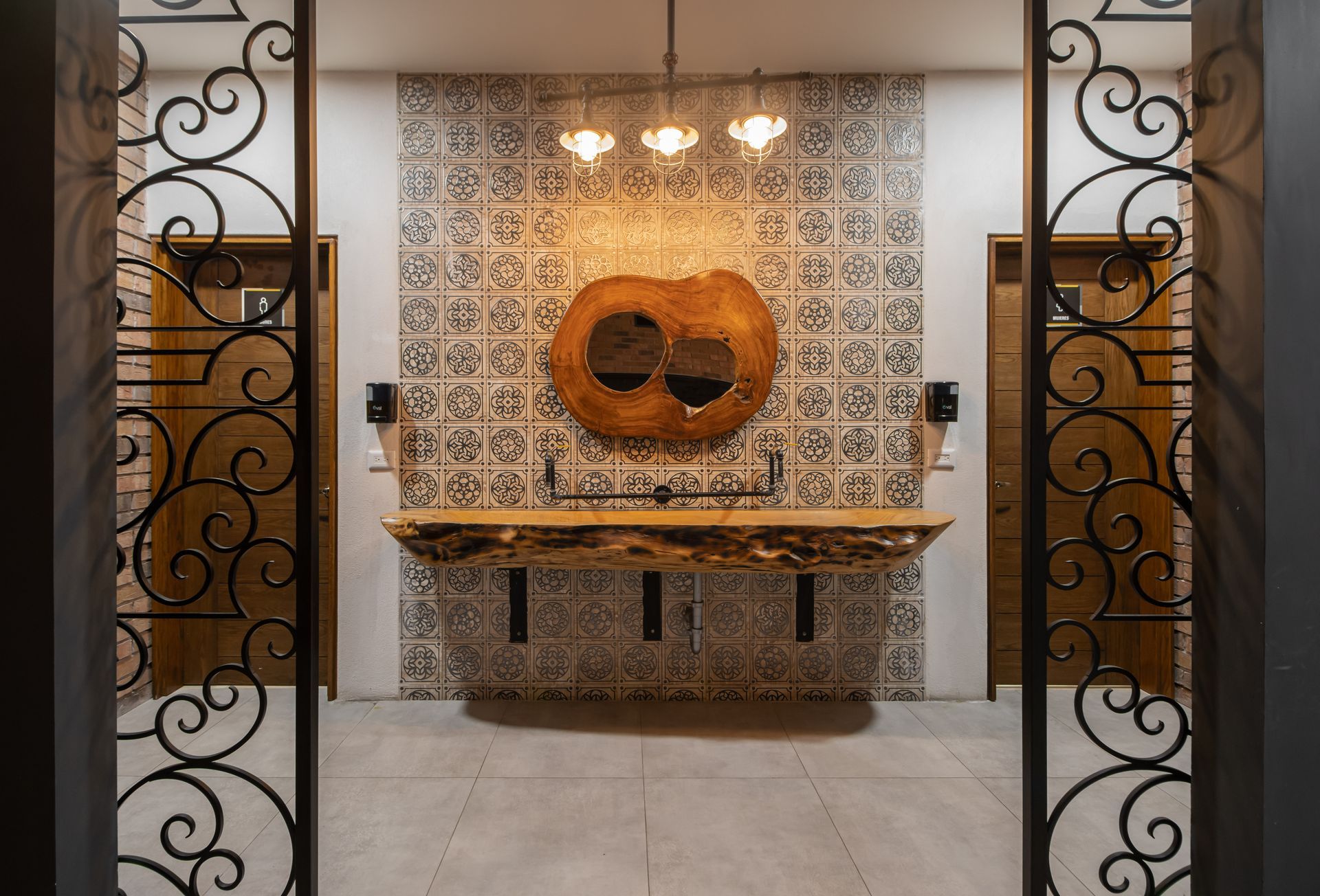 Interior ornamentado con azulejos y una escultura de máscara de madera tallada sobre una mesa consola decorativa.