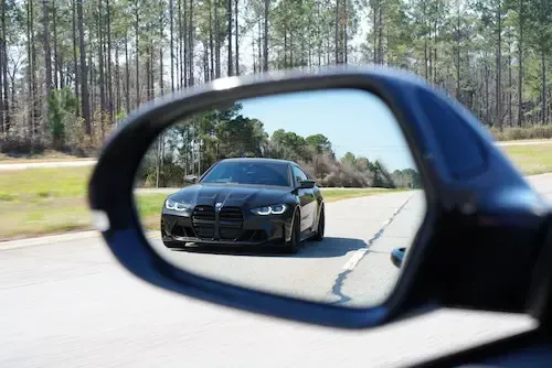 A car is driving down a road in the rear view mirror | Redline Automotive