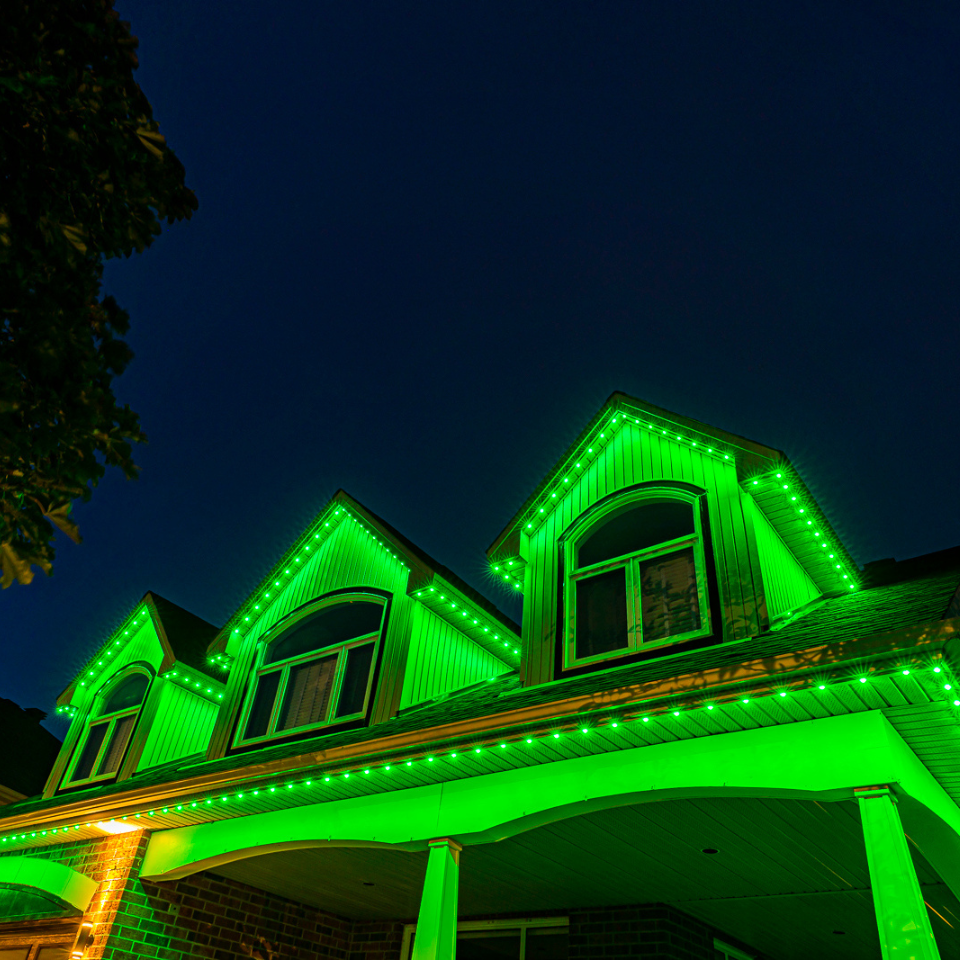 A house is lit up with green lights at night.