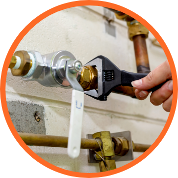 A person using a wrench to tighten a nut on a plumbing pipe in an indoor setting.