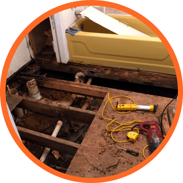 Bathroom renovation: exposed floorboards, plumbing, and a yellow bathtub; tools scattered about.