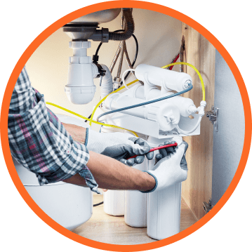 Plumber in gloves, installing water filter system under sink.