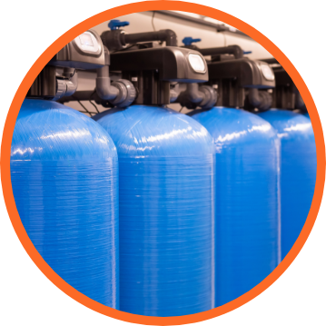 Blue water filtration tanks in a row, with black piping and controls.