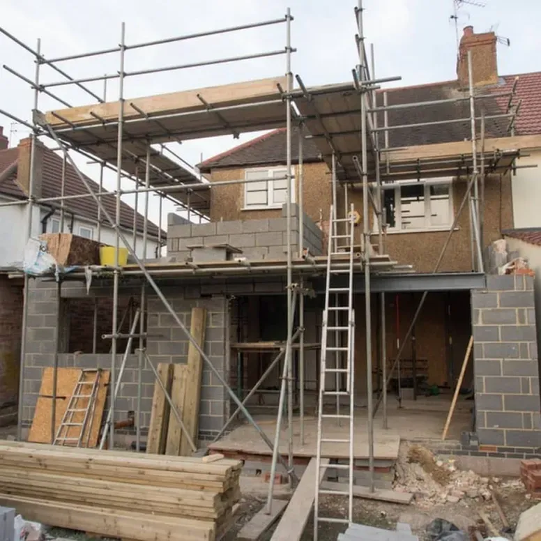 A house under construction with scaffolding and a ladder