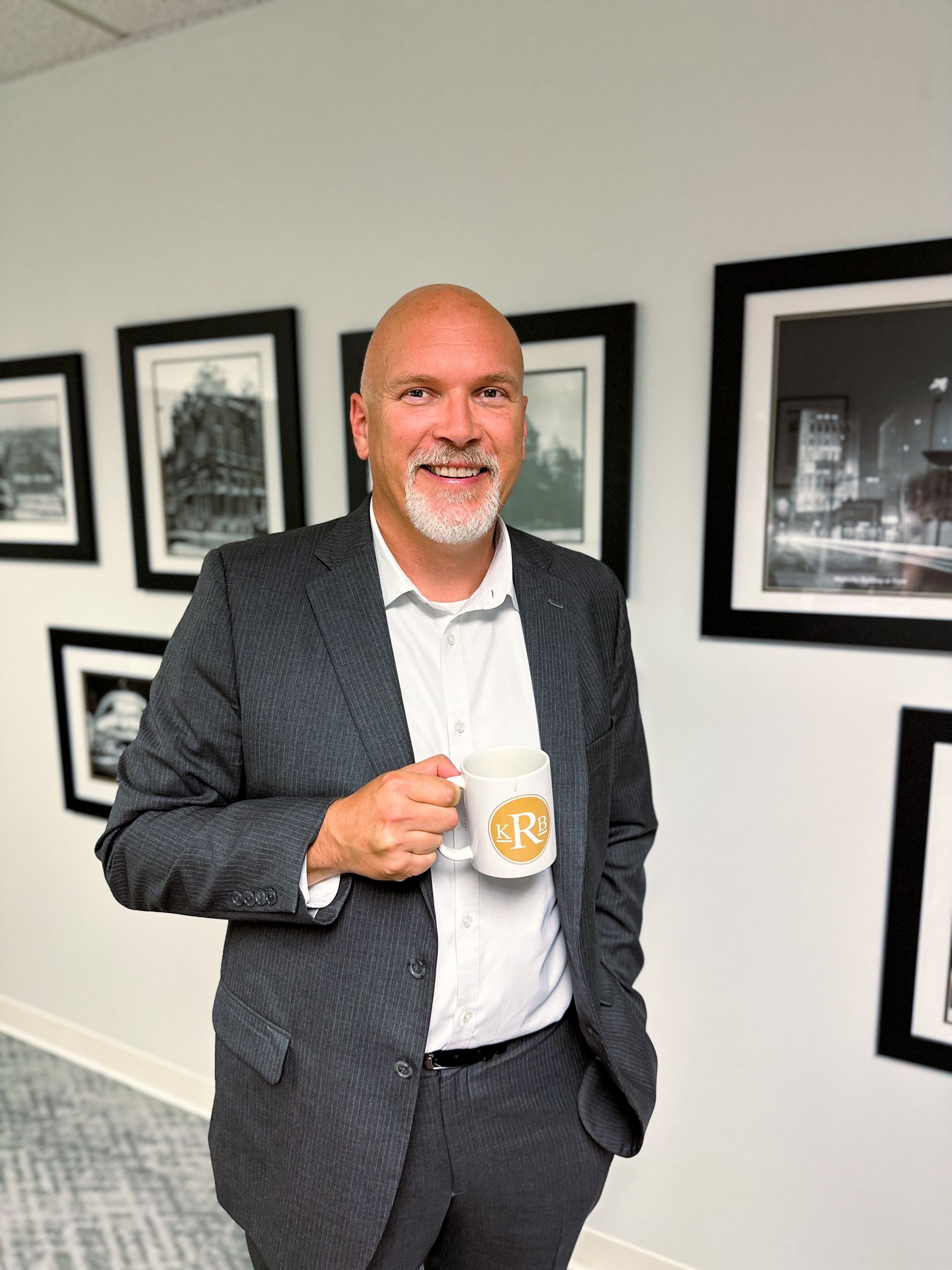 A man in a suit is holding a mug with the letter r on it.