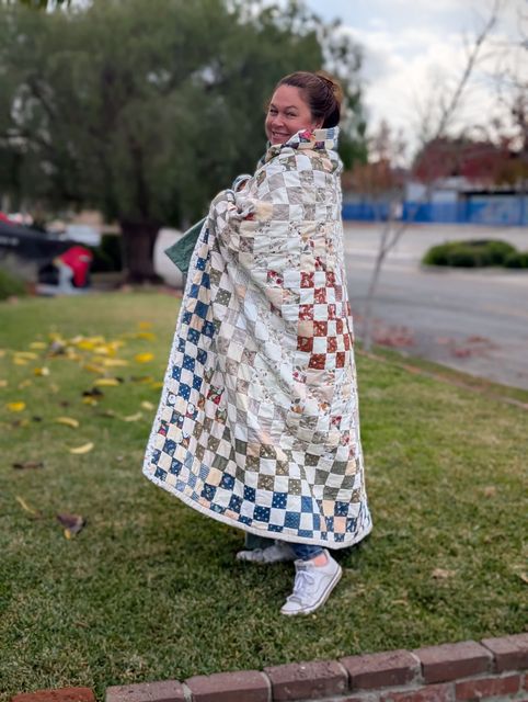 Photo of creator Roya Dedeaux wrapped in a quilt she made