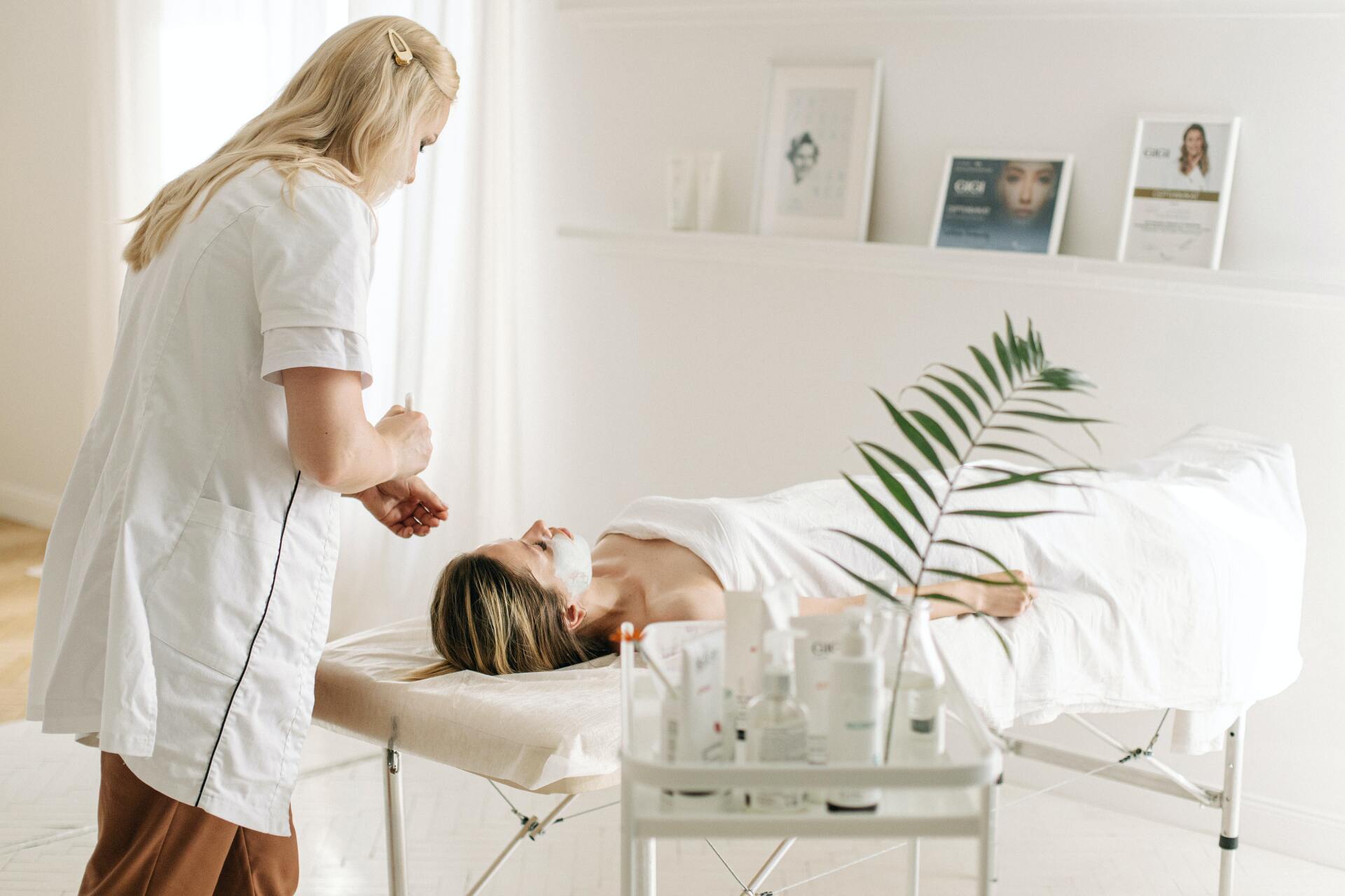 Dermatologist applying facial mask on customer's face