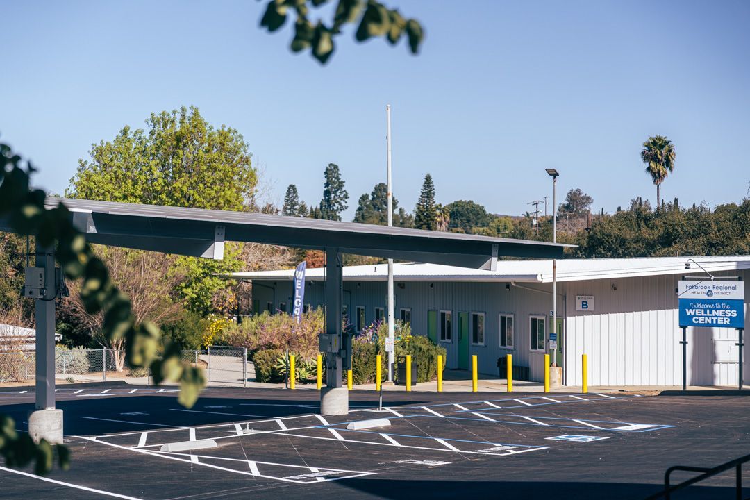 A parking lot in front of a building with a canopy over it.