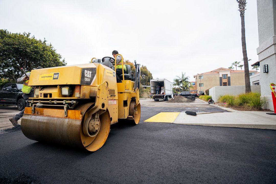 A man is driving a yellow roller on a road.