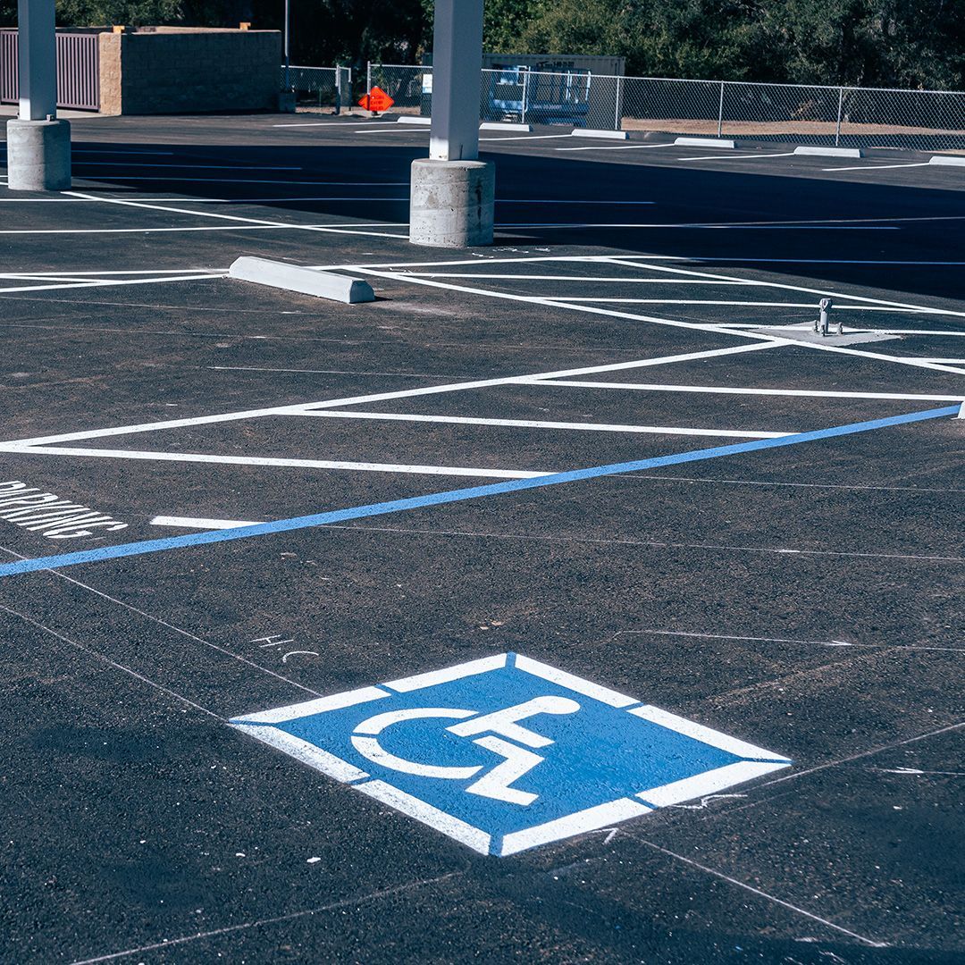 Accessible parking space marked on dark asphalt with a blue wheelchair symbol and white lines.