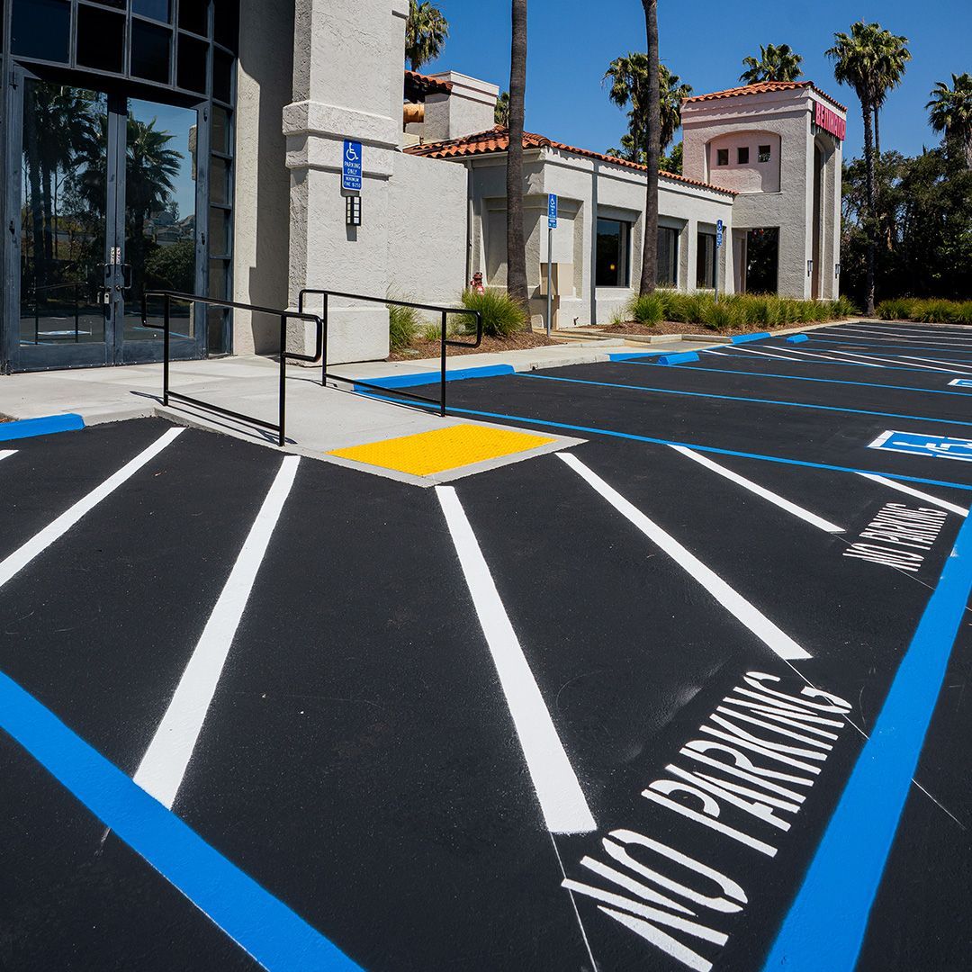 Accessible parking spaces with blue lines and a “No Parking” sign beside a building entrance.