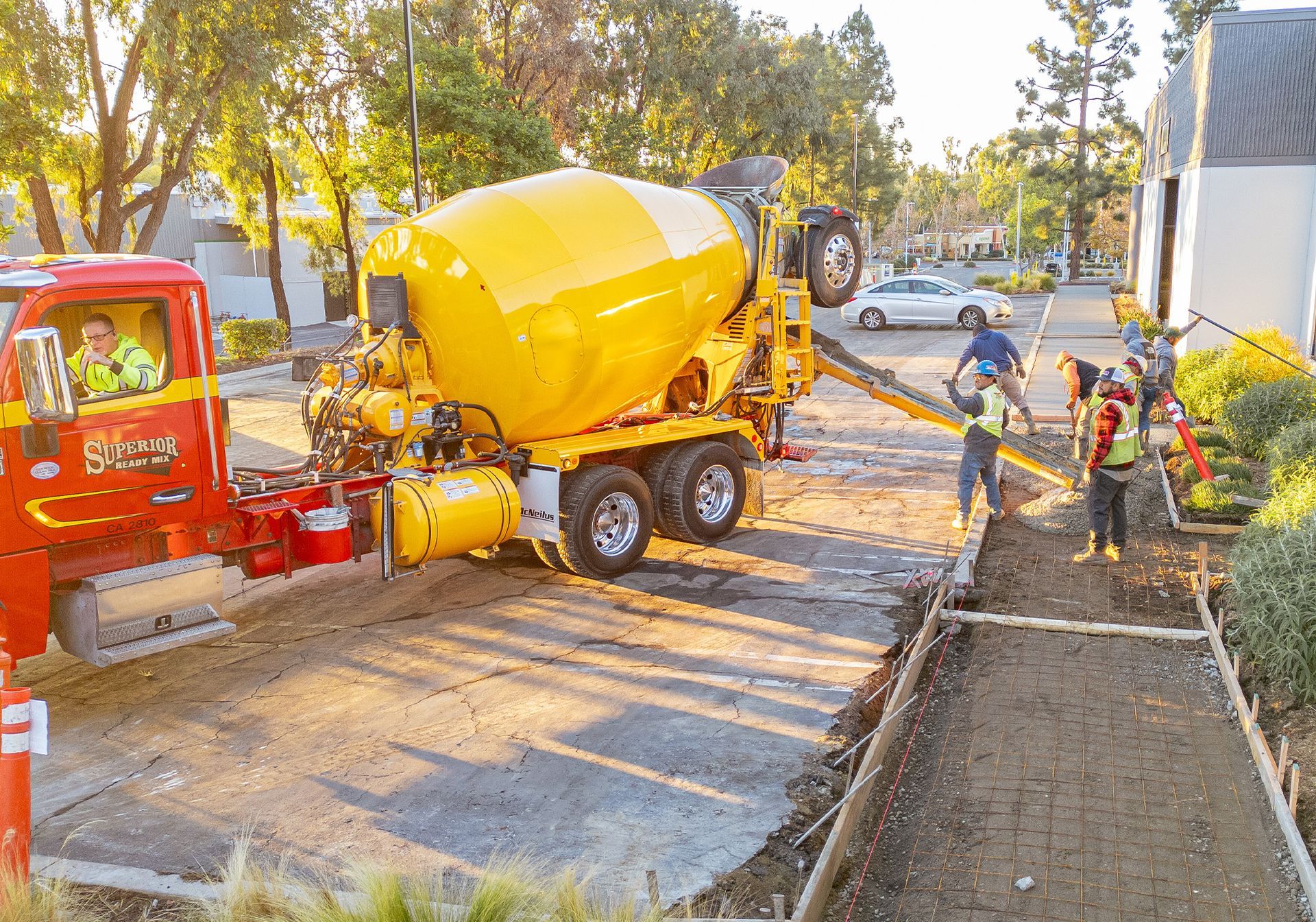 A yellow concrete mixer is being used to pour concrete into a driveway.