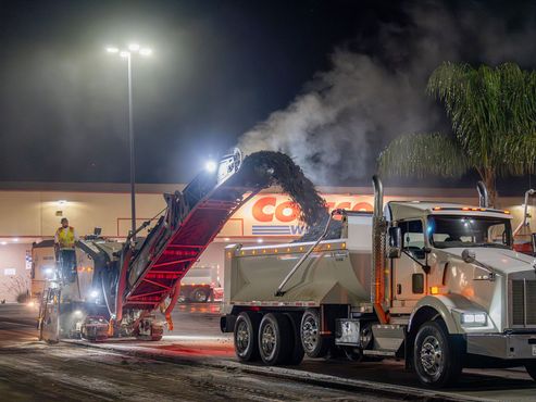 A dump truck is parked in front of a costco store at night.