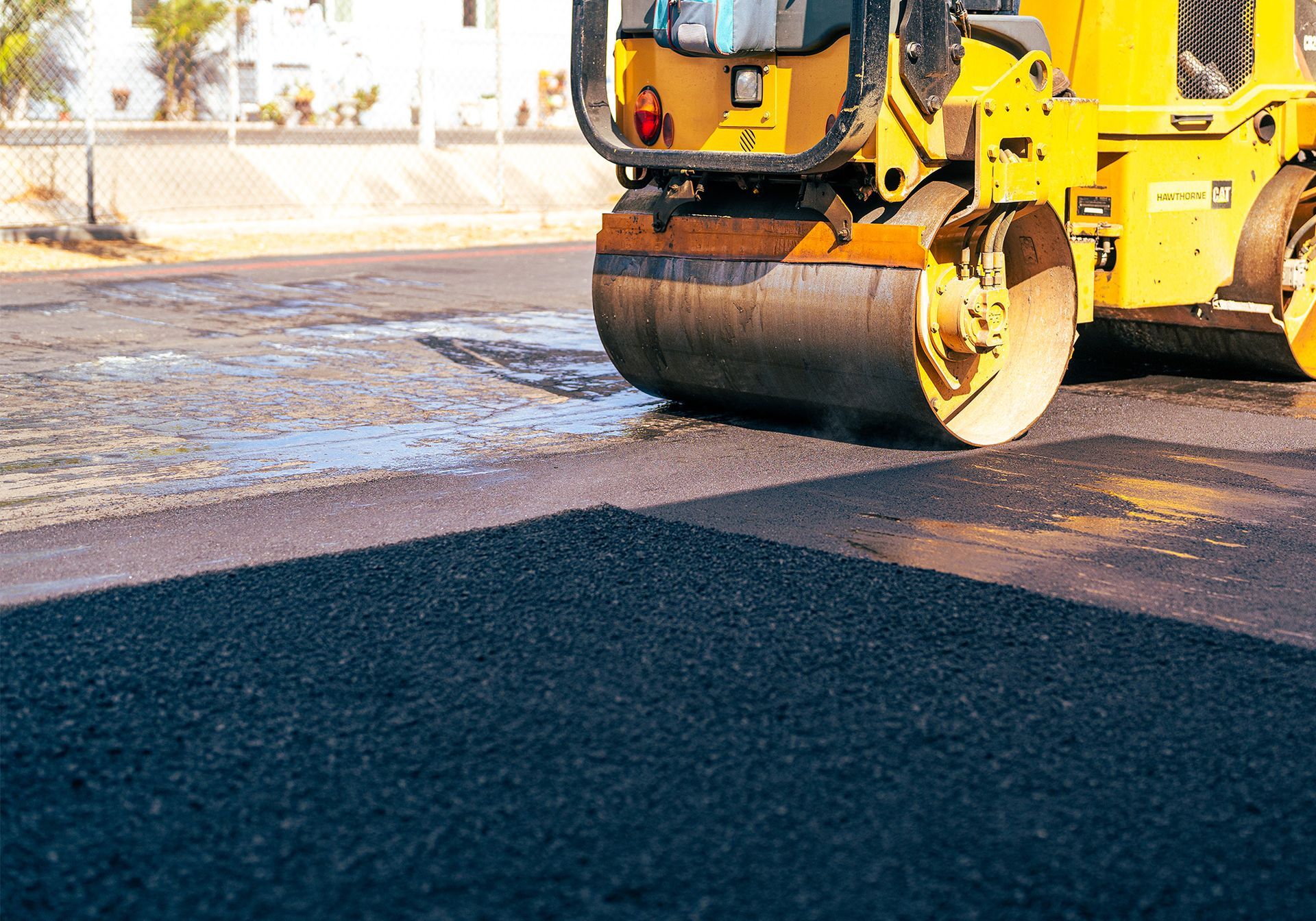 A yellow roller is rolling asphalt on a road.
