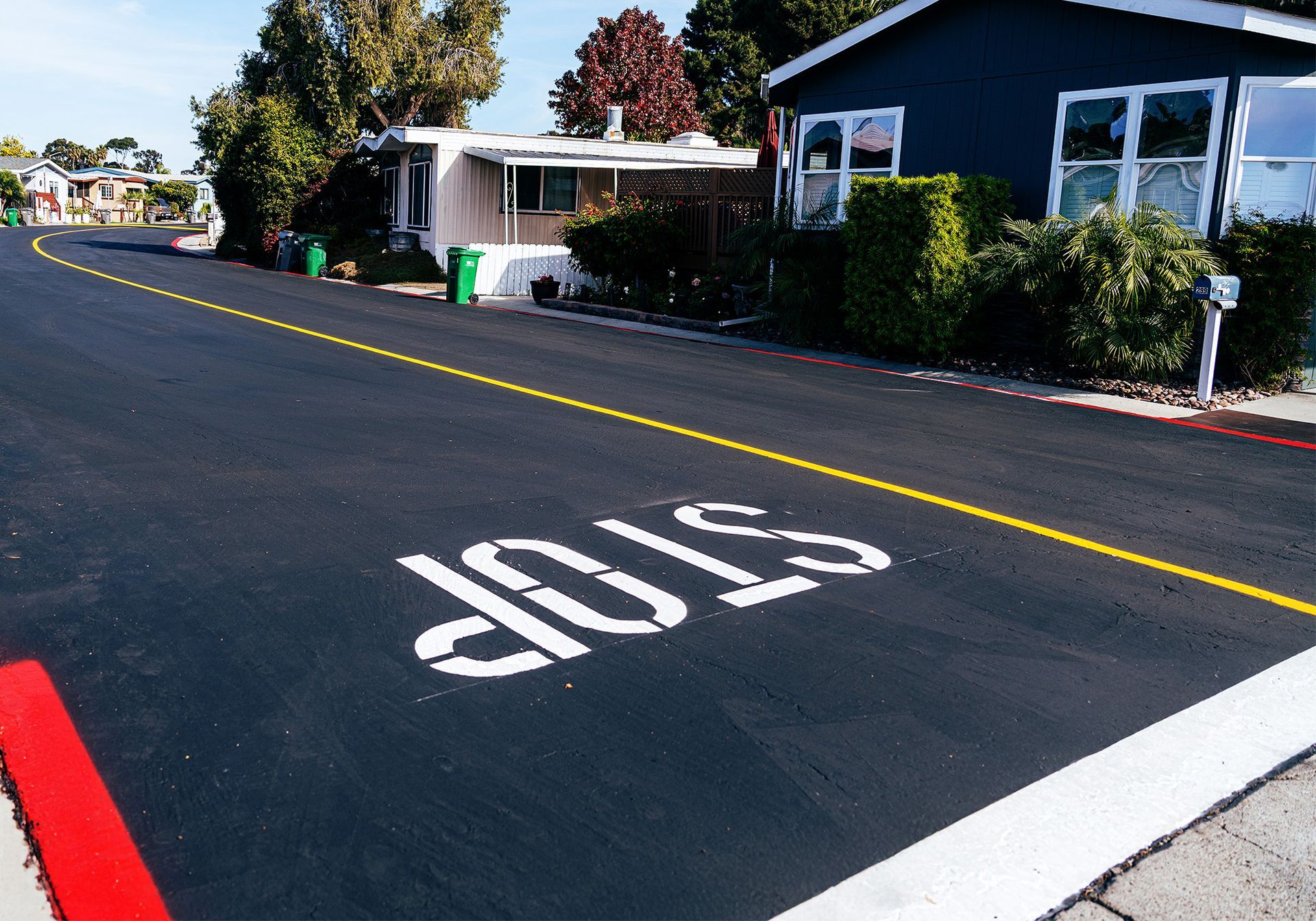 Marked stop line on a residential street with houses and a painted stop sign on the pavement
