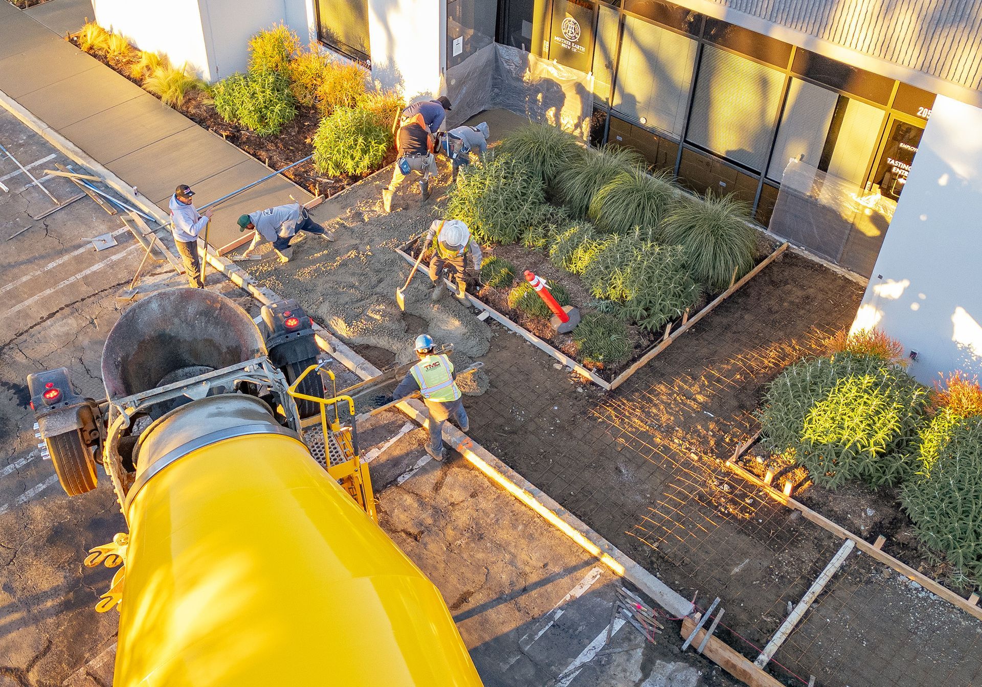 A group of people are working on a concrete driveway in front of a building.