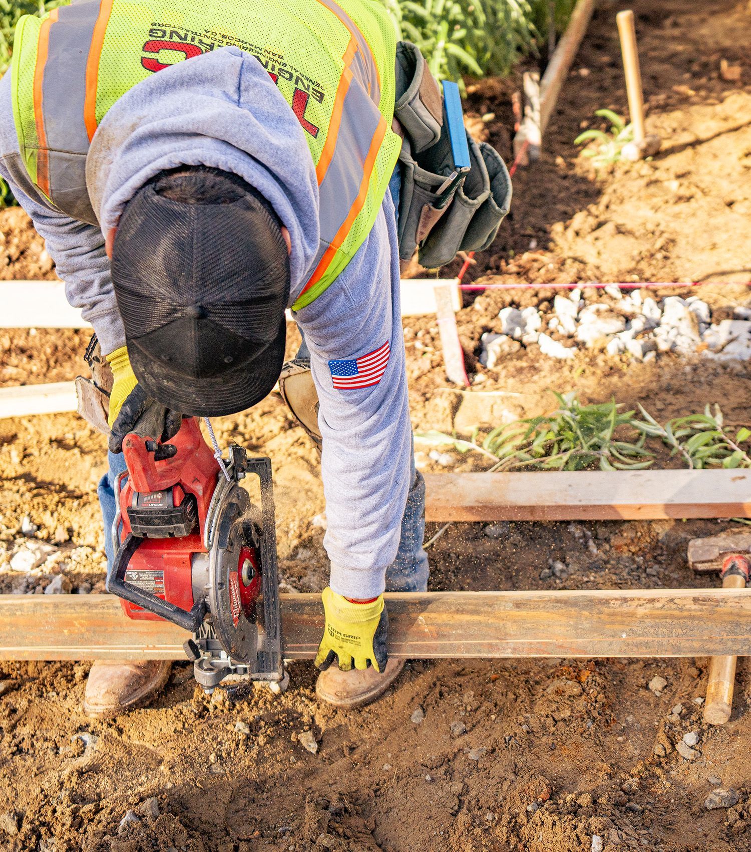 Worker using a red circular saw to cut wood on a construction site