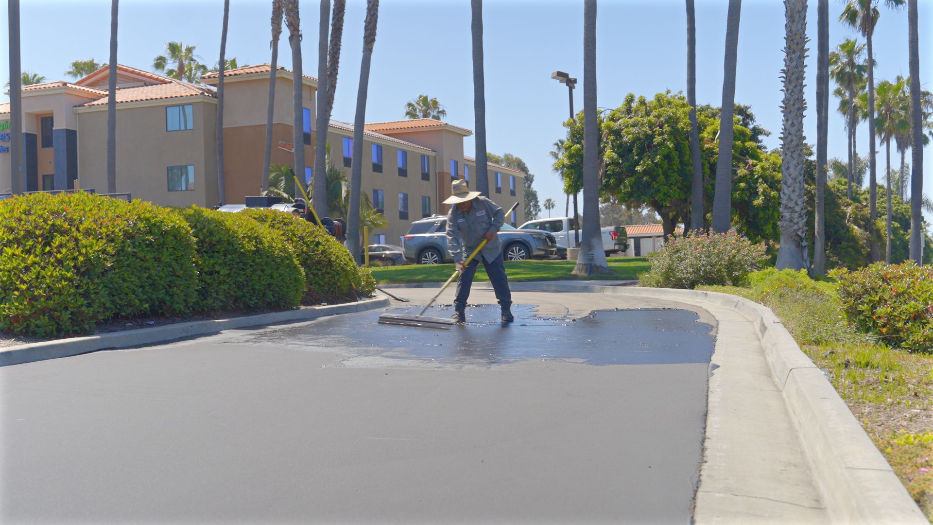 A man is cleaning a parking lot with a broom.