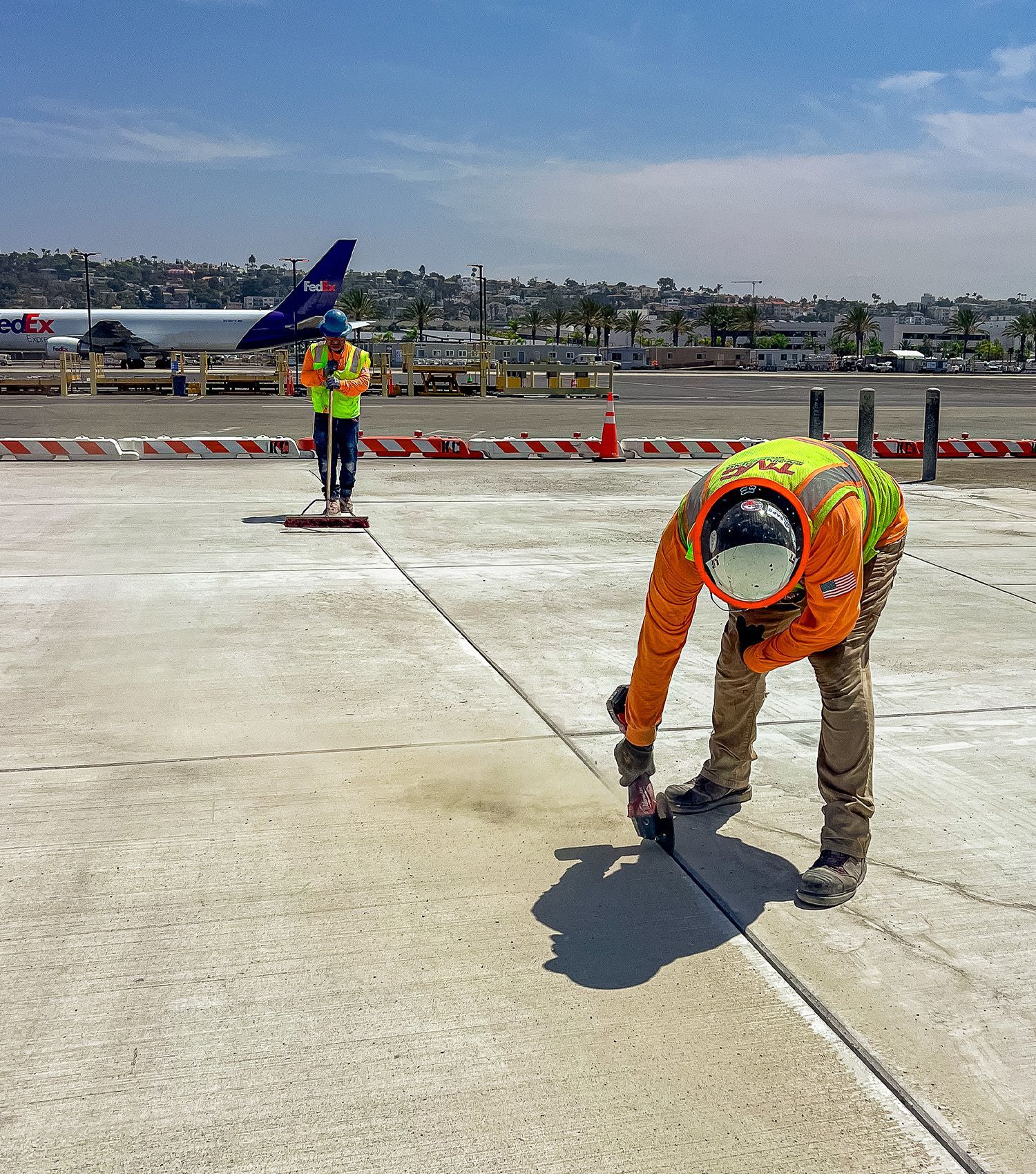 Two construction workers are working on a concrete surface.