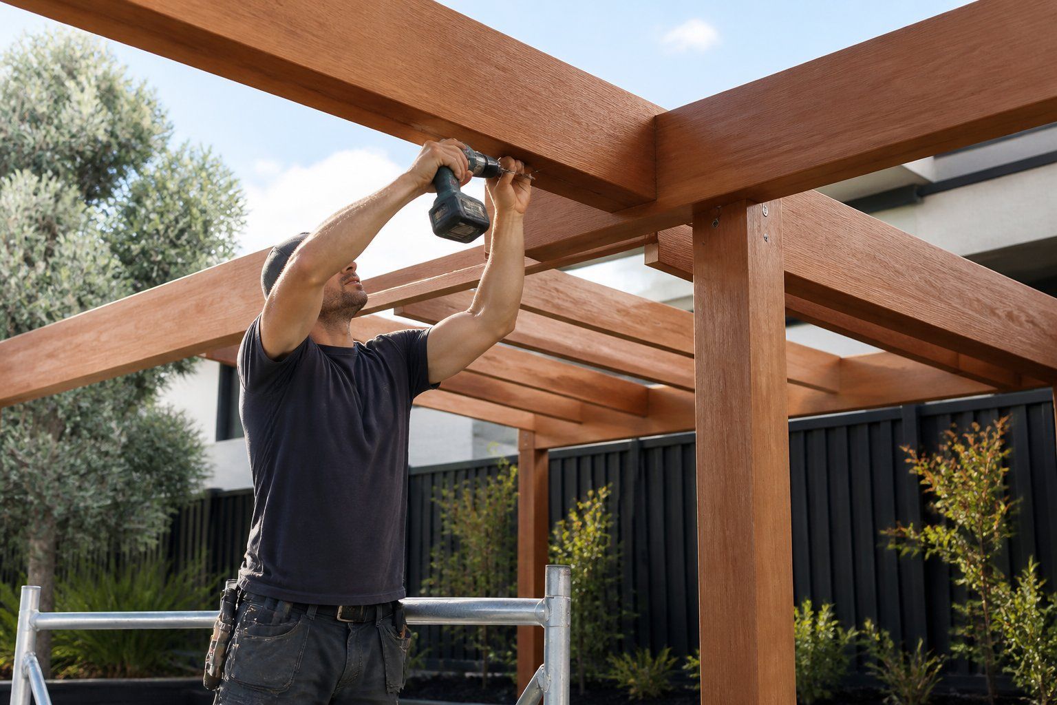 Person drilling into a wooden pergola frame outdoors with a power drill