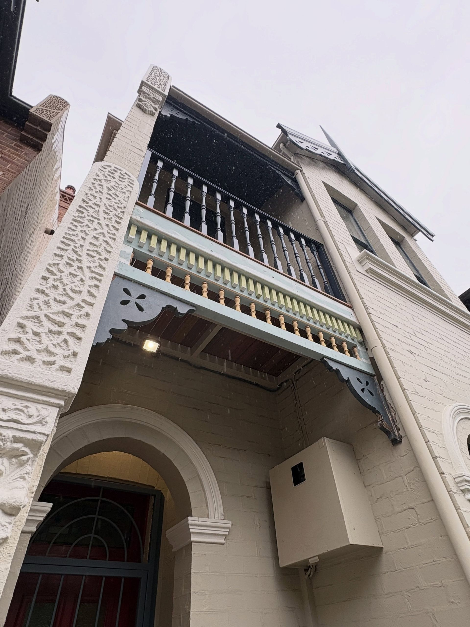 Low-angle view of a cream-colored building facade with ornate balconies and an arched doorway