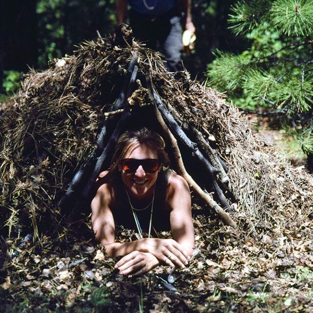 A woman wearing sunglasses is laying in a pile of leaves