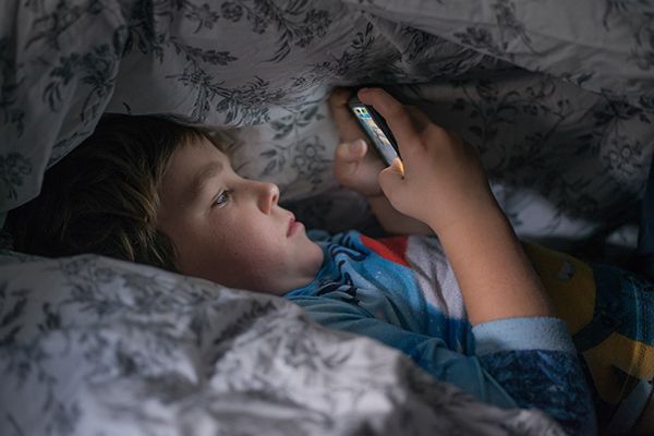  child reading under a blanket