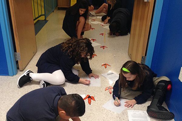 A group of children are kneeling on the floor and drawing footprints on the floor